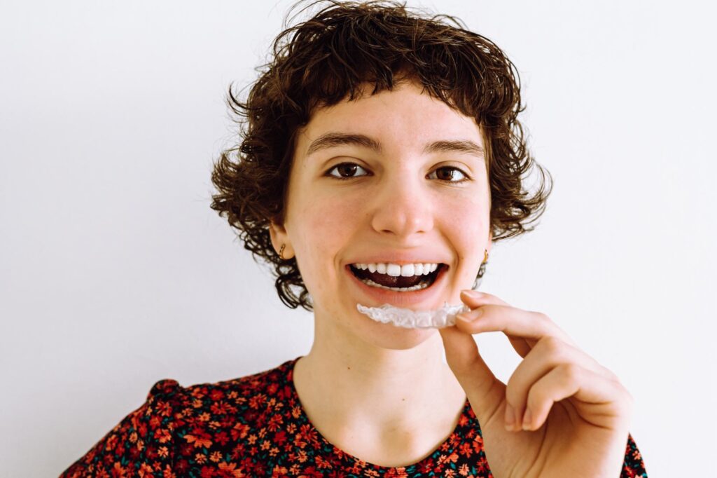 Young woman holding a clear Invisalign aligner
